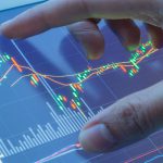 Mężczyzna dotyka ekranu, na którym wyświetlają się wykresy na rynku forex waluty